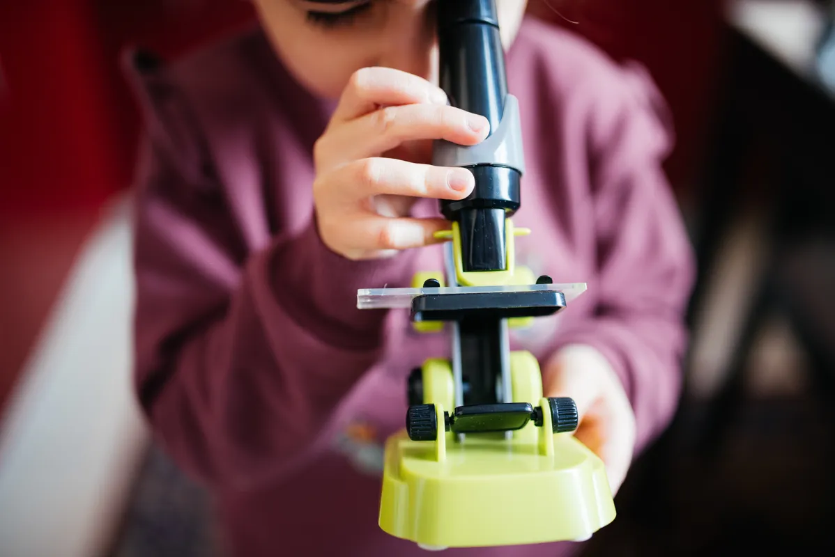 Child looking through a toy microscope